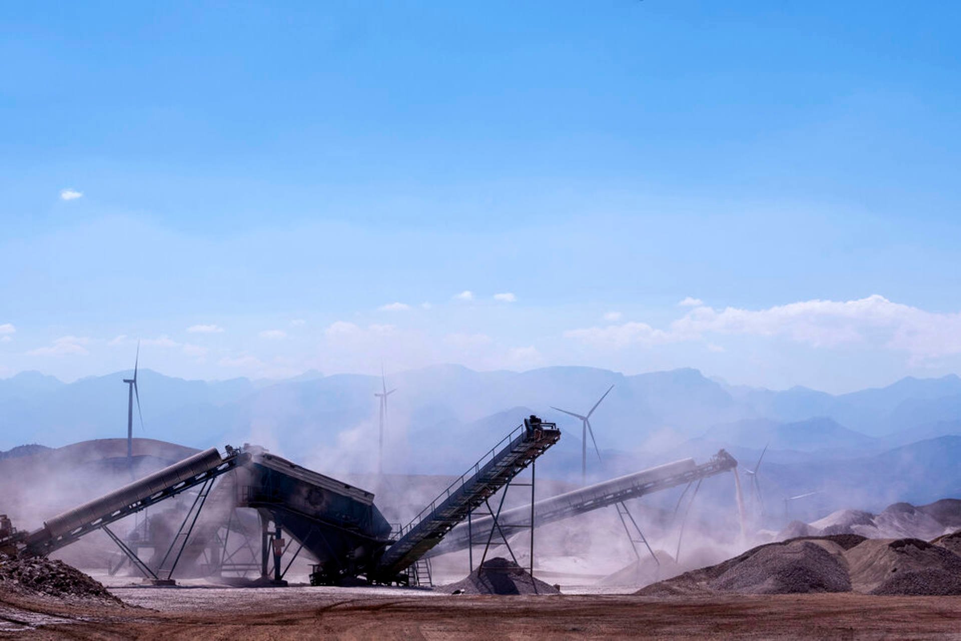 A substantial gravel pile set against a backdrop of towering mountains, showcasing a natural landscape.